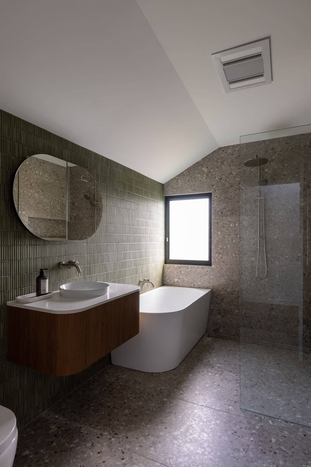 Bathroom with green tiles, terrazzo floor and freestanding bath