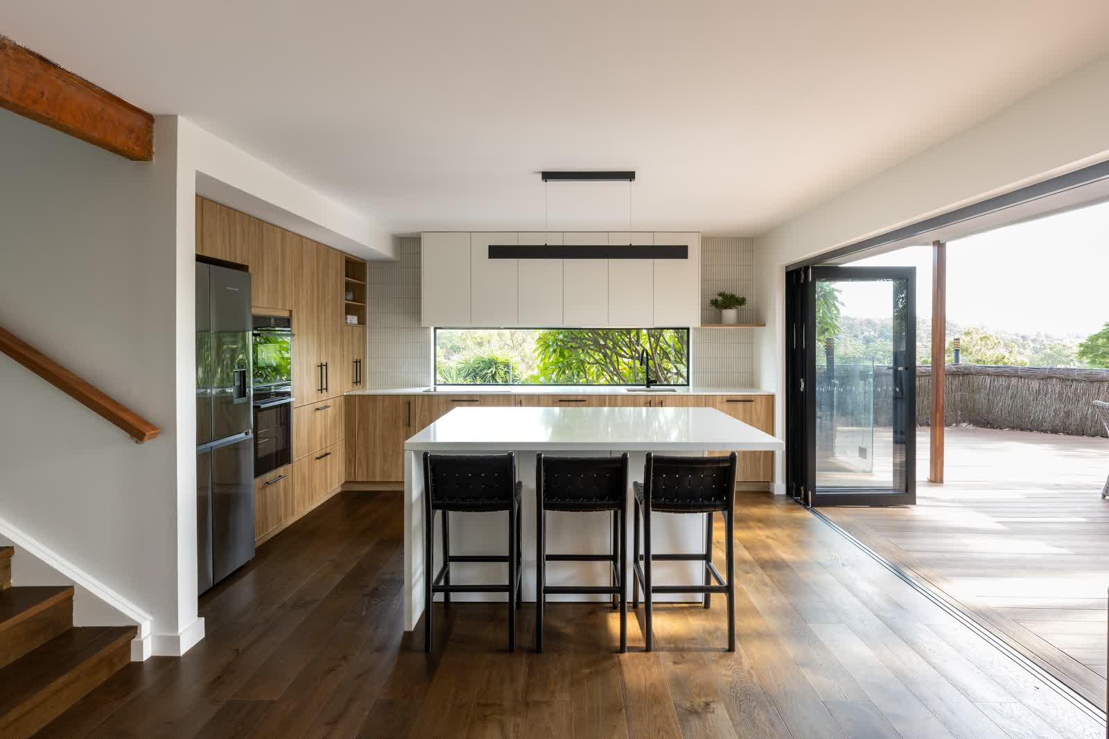 Open-plan kitchen with bifold doors open to the deck