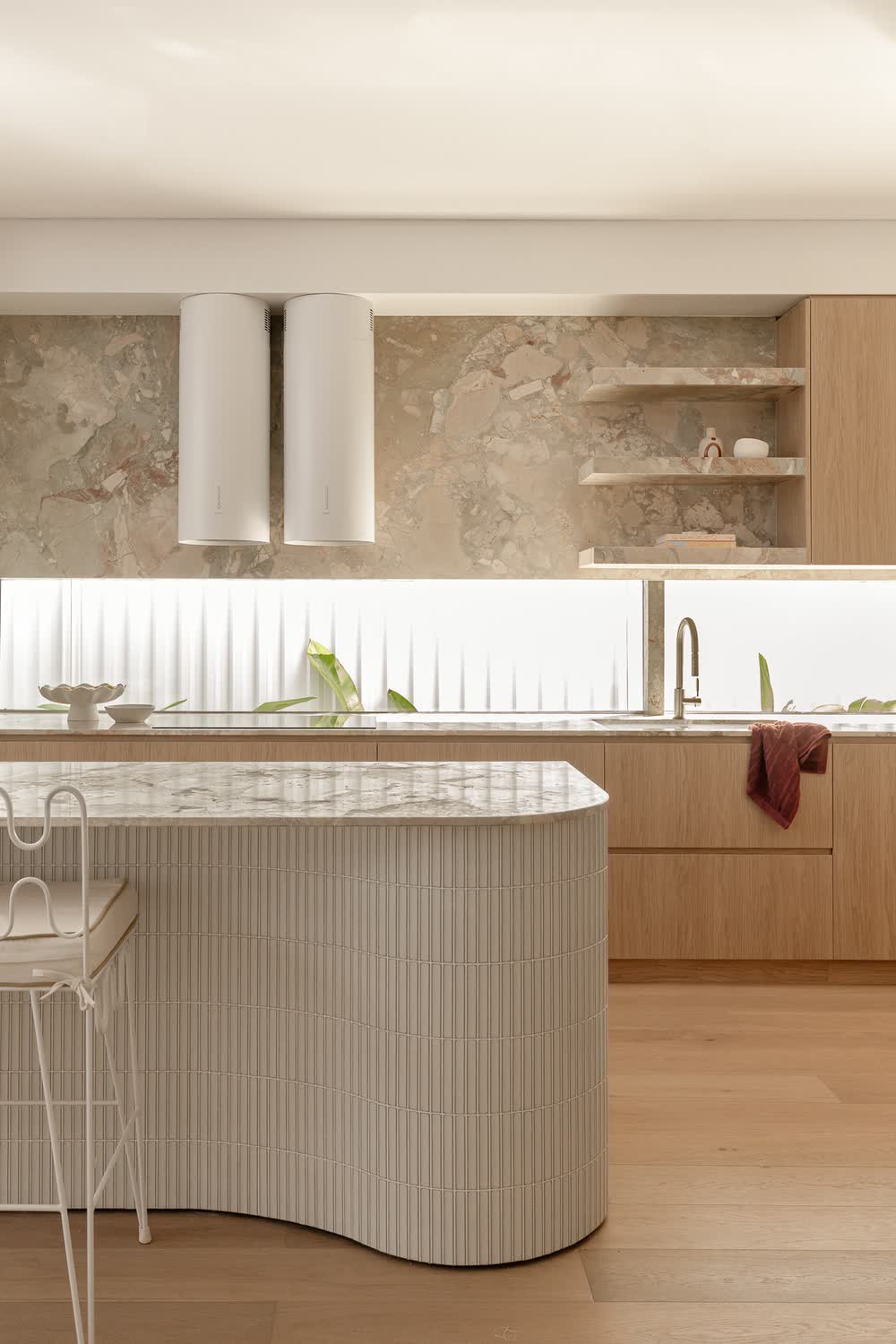 Kitchen with a curved fluted island and stone splashback
